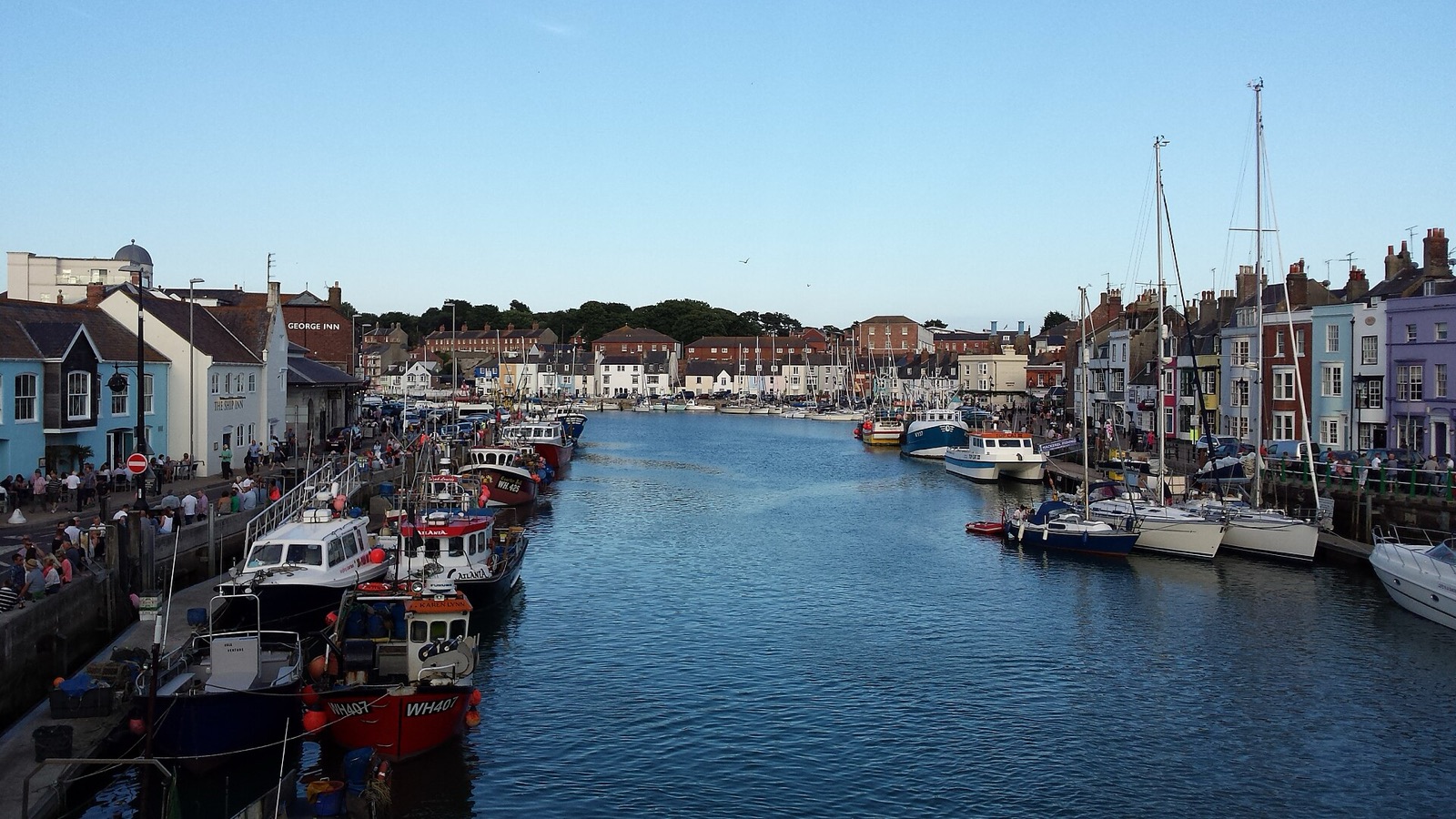 Weymouth harbour with fishing boats moored along the quay and terraced houses