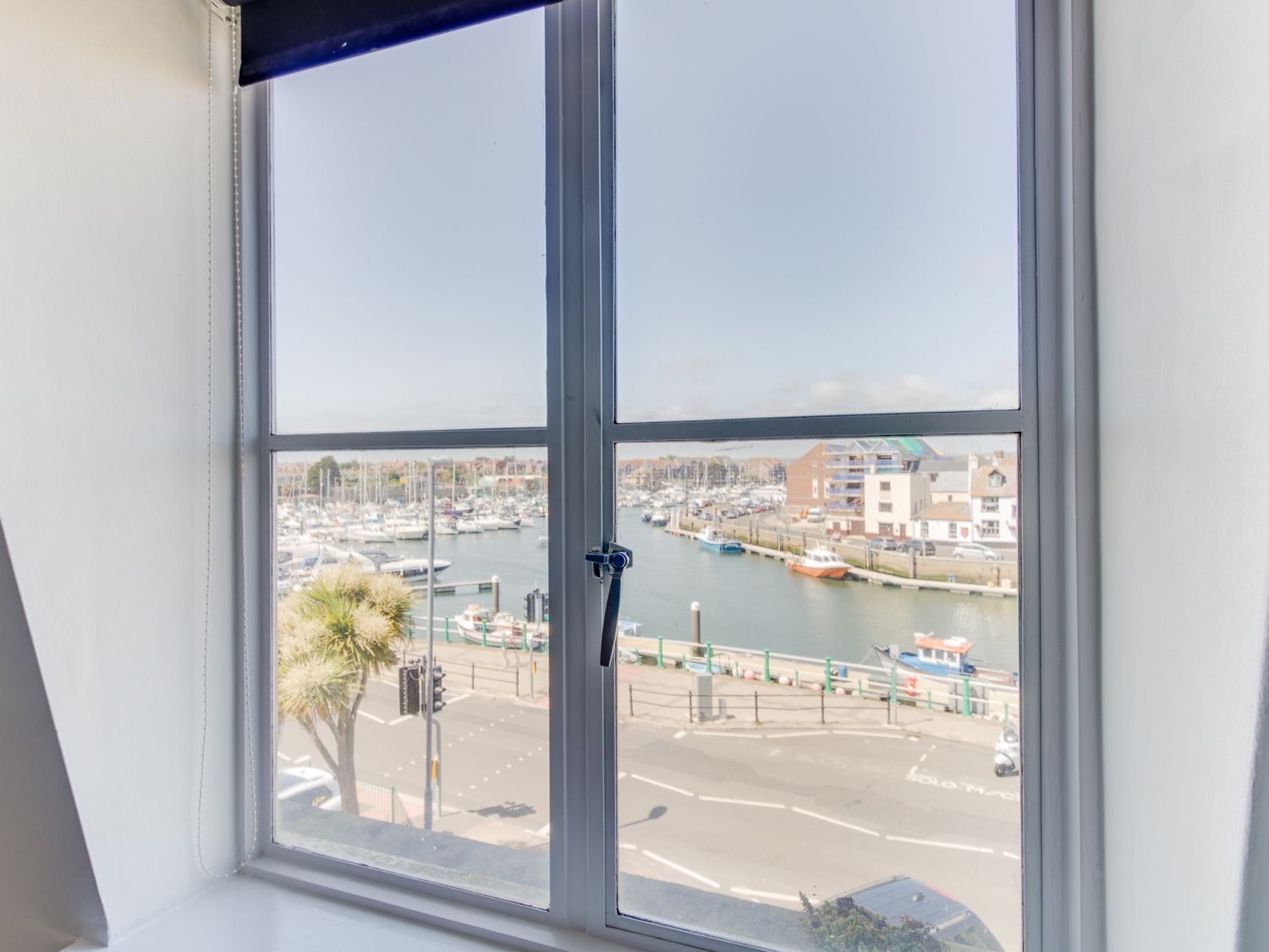 The view from Sailor's Watch: boats moored along Weymouth's inner harbour seen through a tall window
