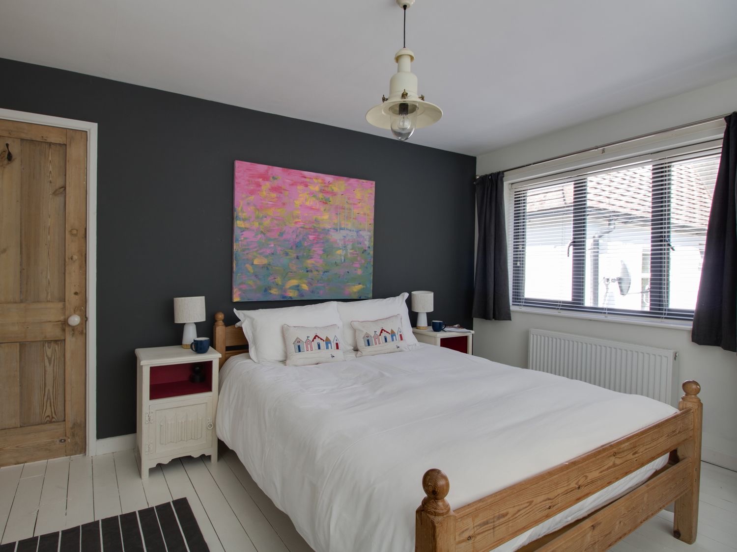 Master bedroom at Sailor's Watch with a wooden bed, white linen and a striped rug