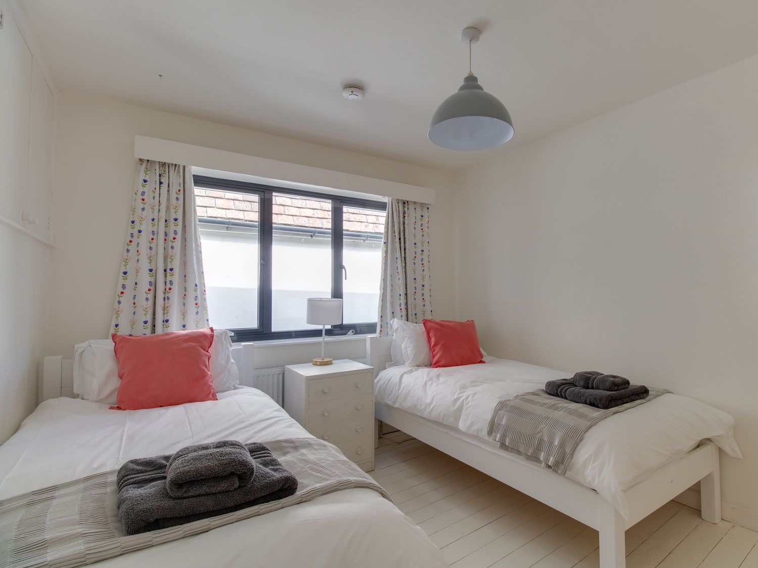 Twin bedroom at Sailor's Watch with coral cushions