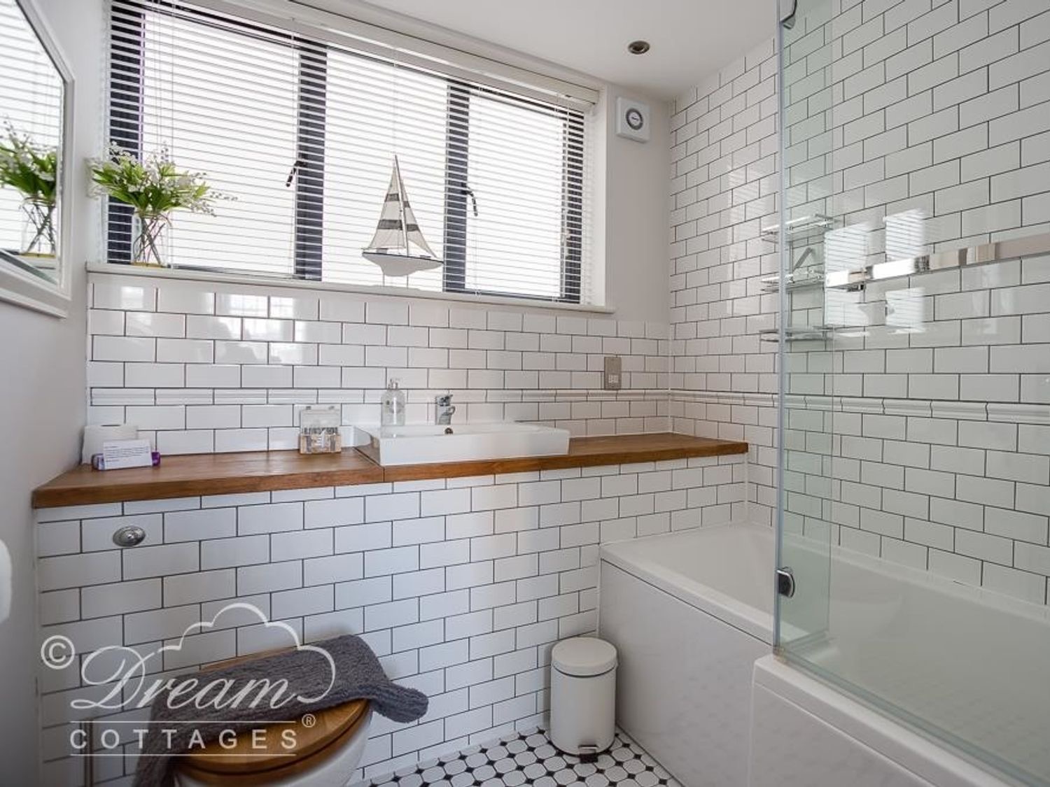 Waterside bathroom with a bath, shower screen and wooden counter