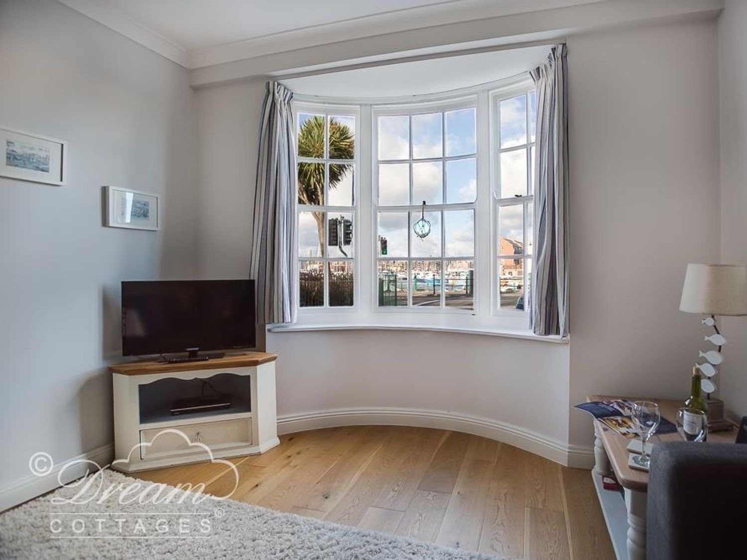 Waterside living room: a bay window onto the harbour with a television and armchair