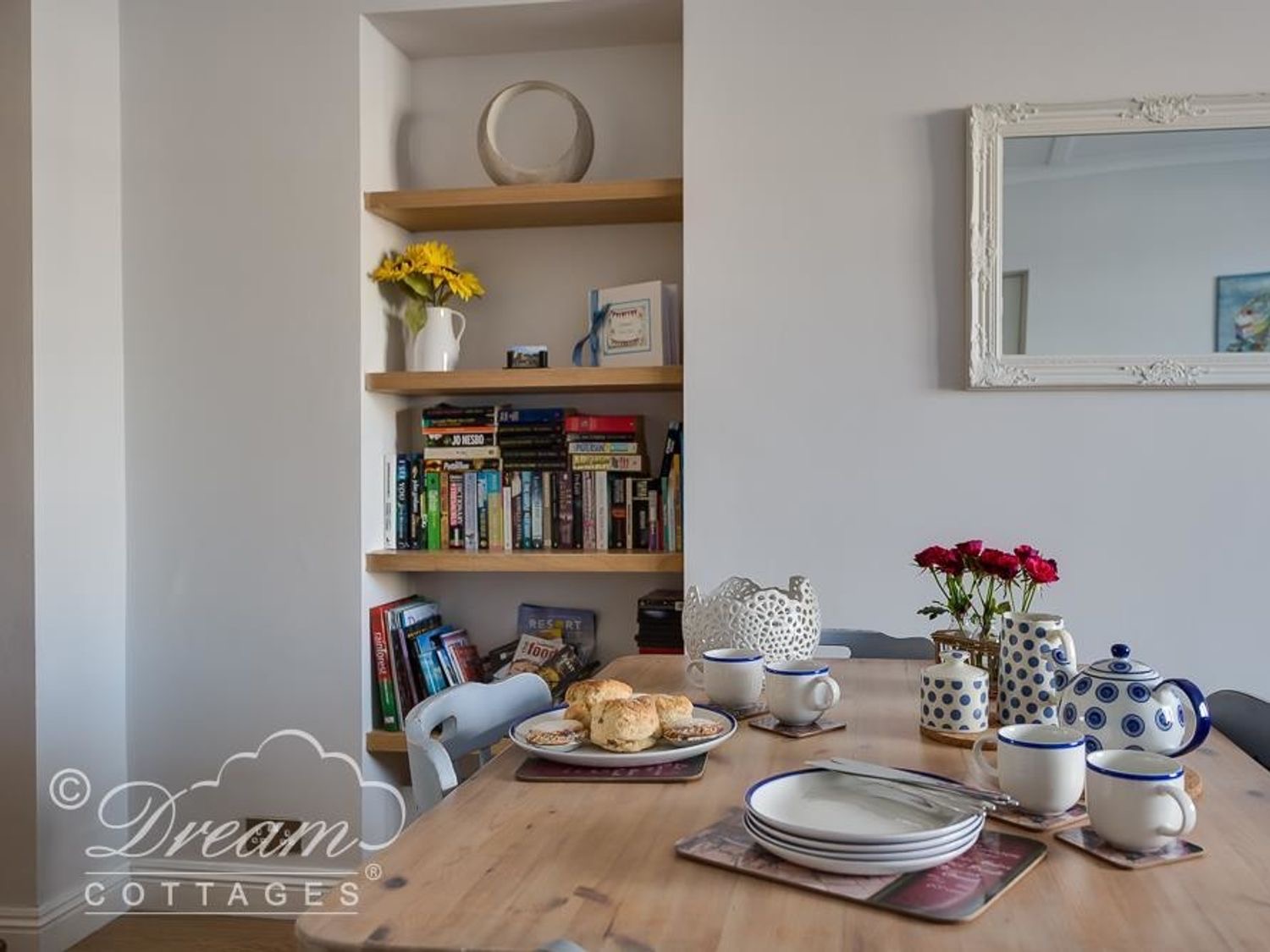 Dining table at Waterside laid with teacups, beside shelves of books