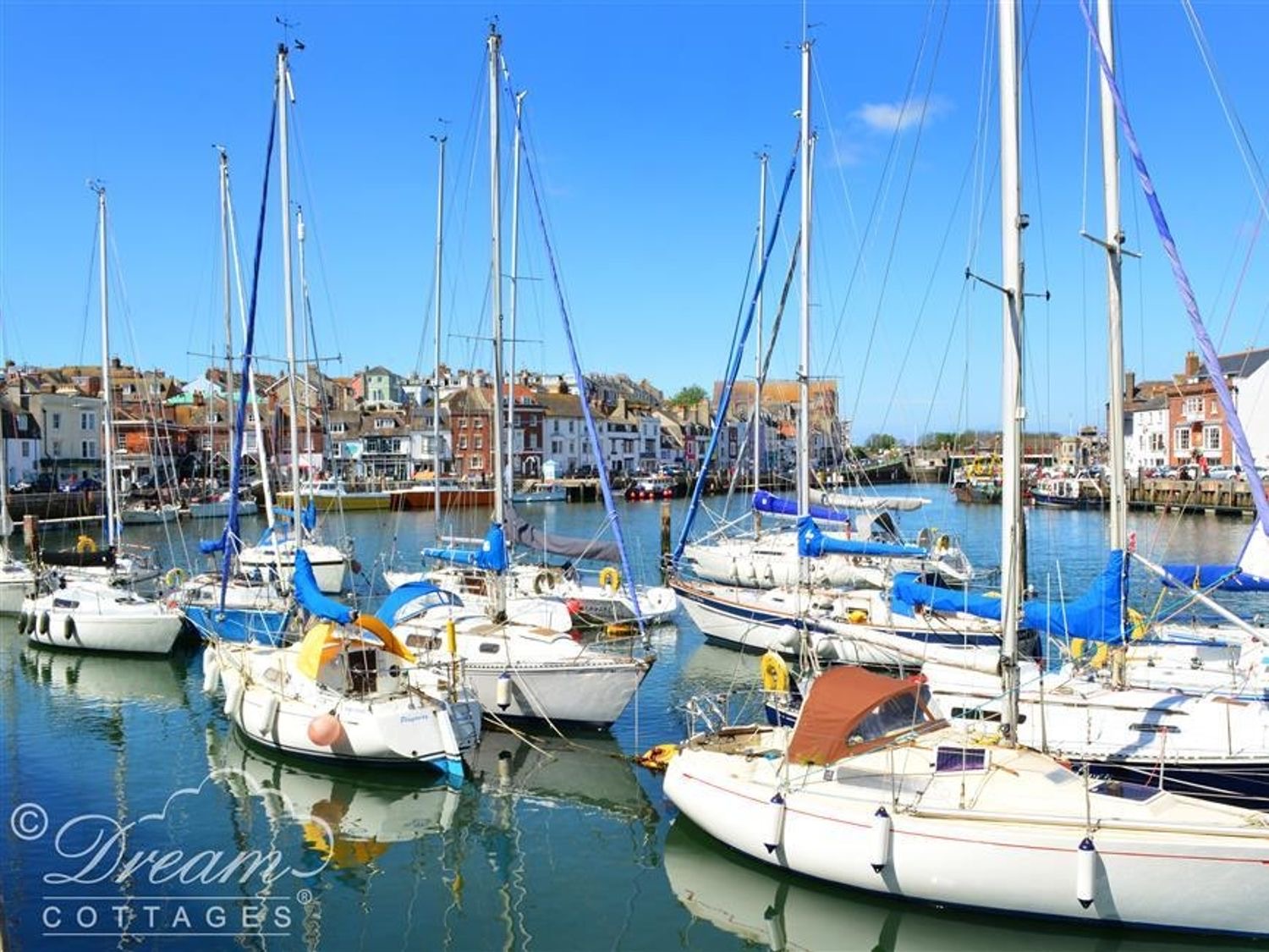 Yachts moored in Weymouth harbour with the town's painted houses behind