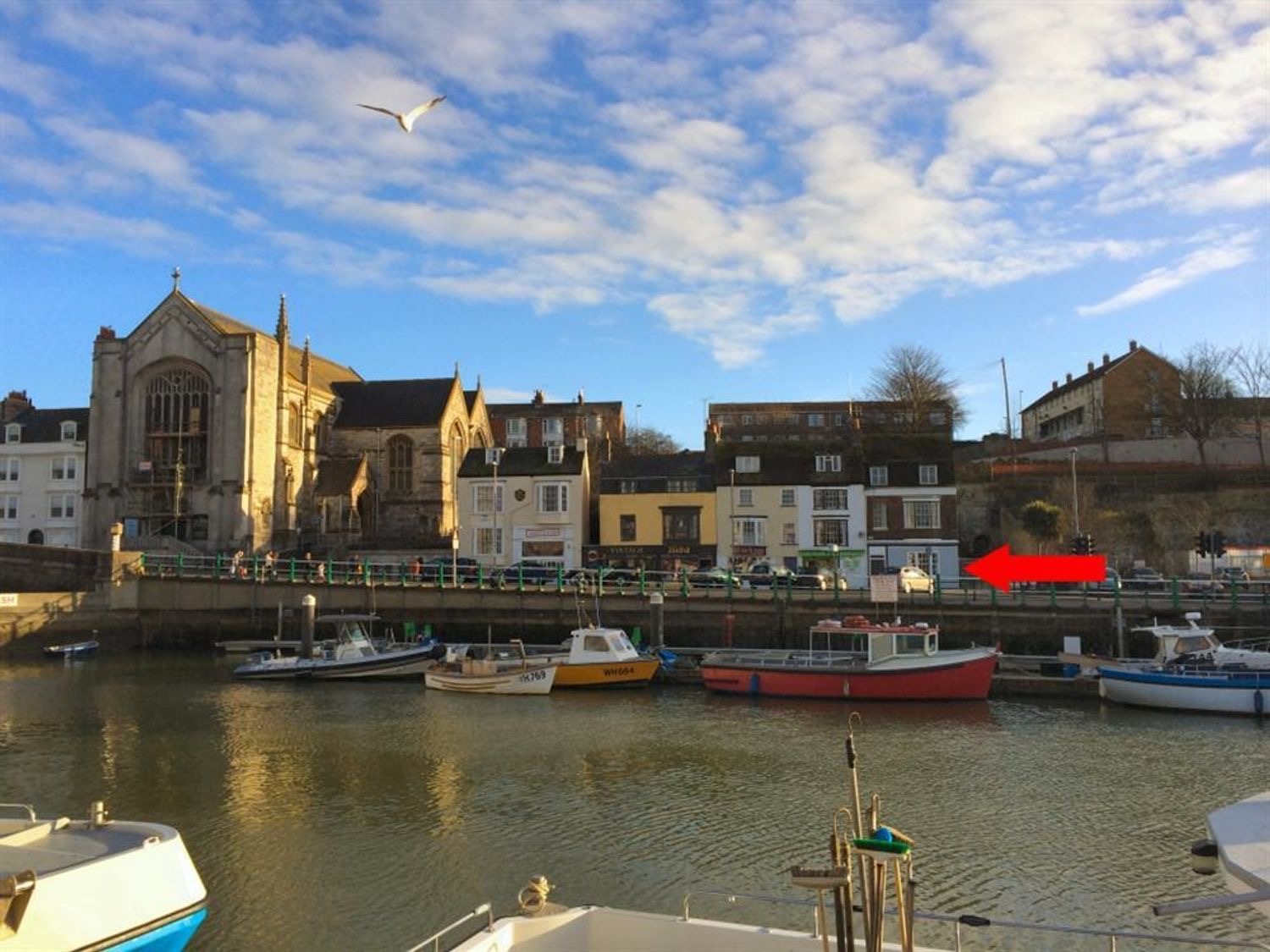 Weymouth's inner harbour at golden hour with fishing boats and the old town behind