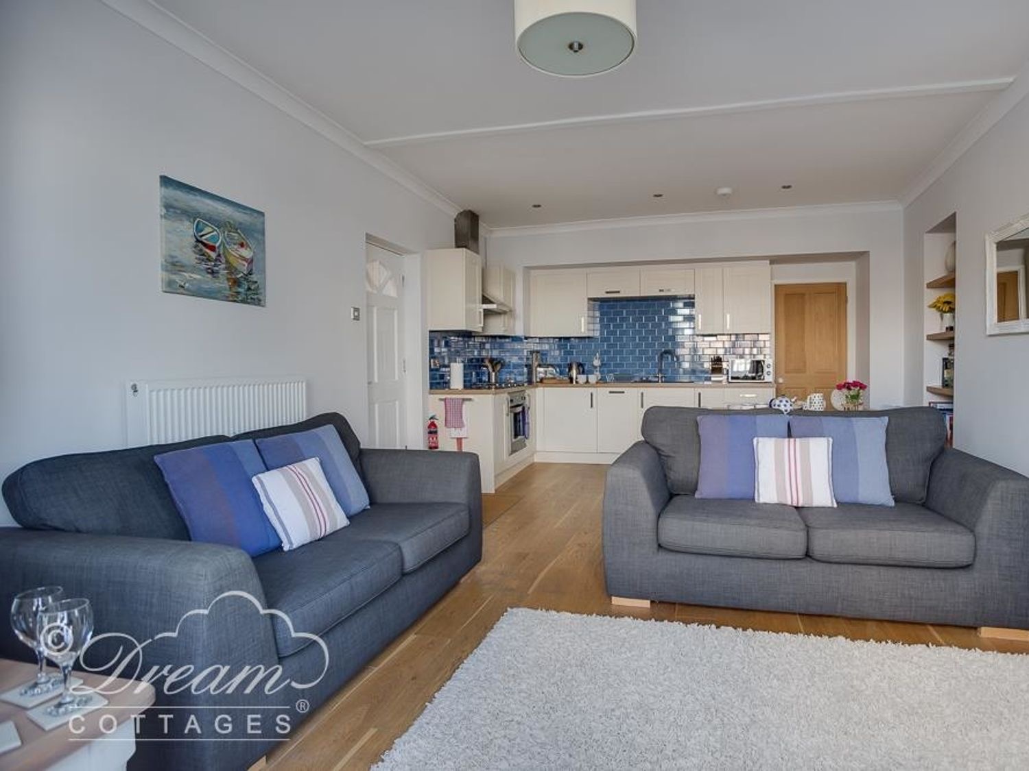Waterside's open-plan living room with two grey sofas and the kitchen beyond