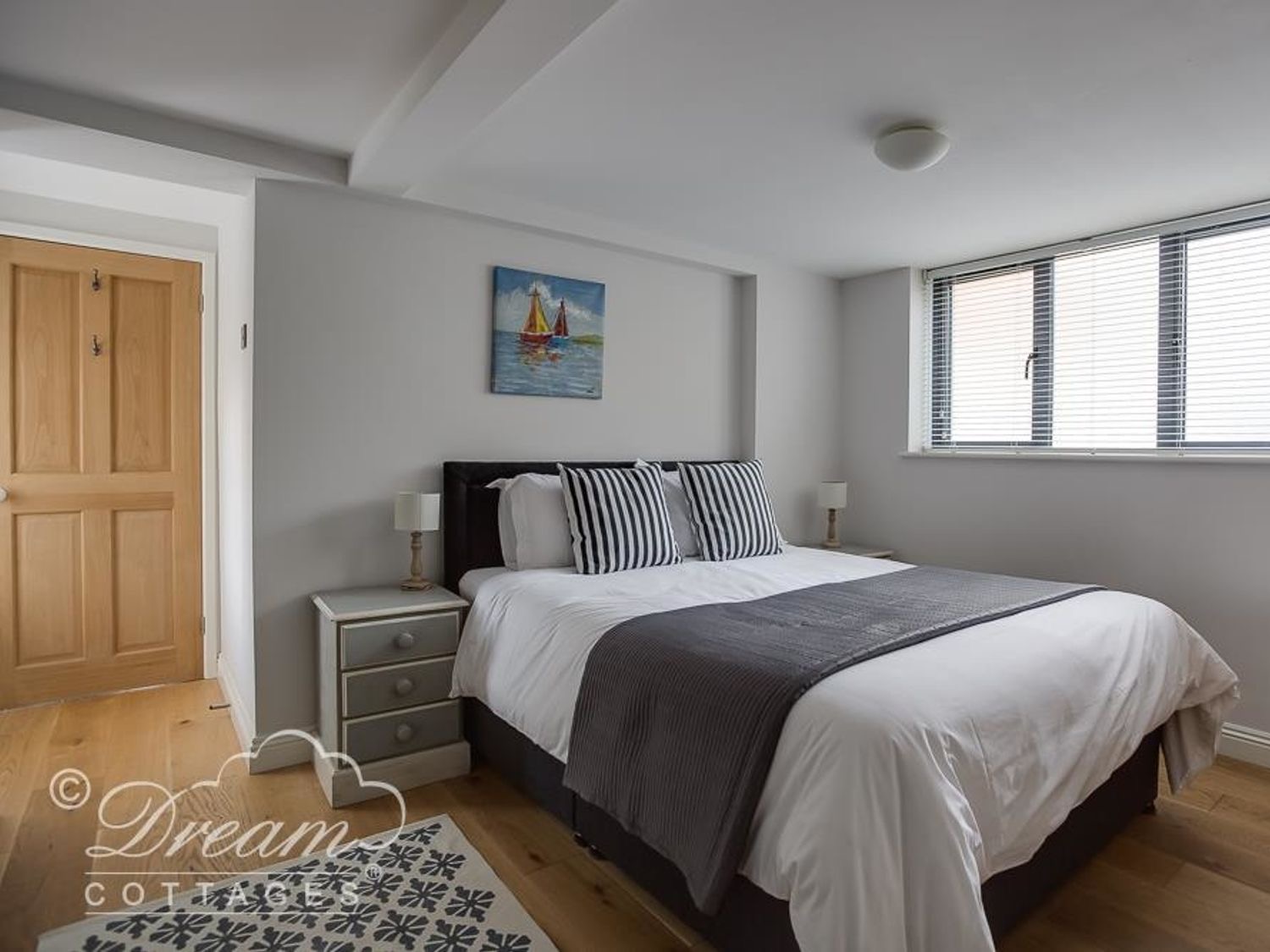 King-size bedroom at Waterside with striped pillows and a painting of sailing boats
